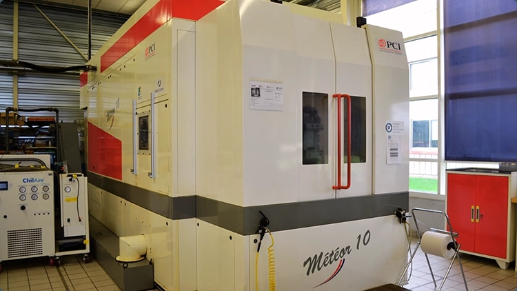 Three-quarter view of the PCI machine with closed doors in the metallurgical R&D workshop.