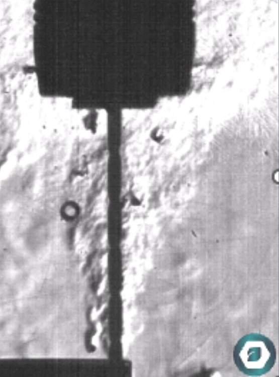 Vue caméra au scanner d'un outil de coupe en pleine opération d'usinage qui projette des copeau et un nuage d'air et de gouttelettes de lubrifiants.